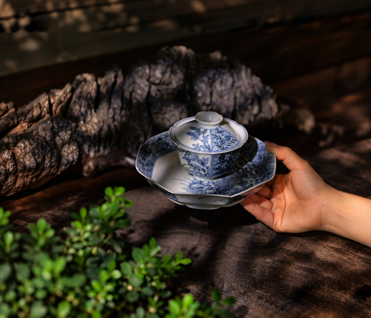 Hand holding a porcelain cup with floral decoration