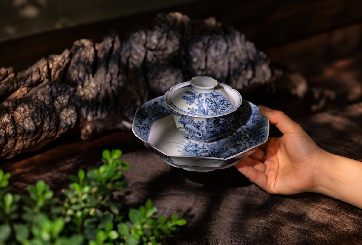 Hand holding a porcelain cup with floral decoration
