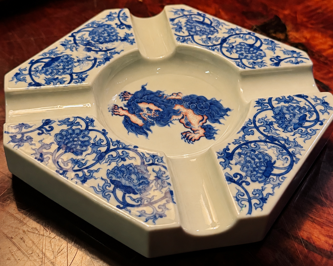Blue-and-white porcelain ashtray on a polished wood table