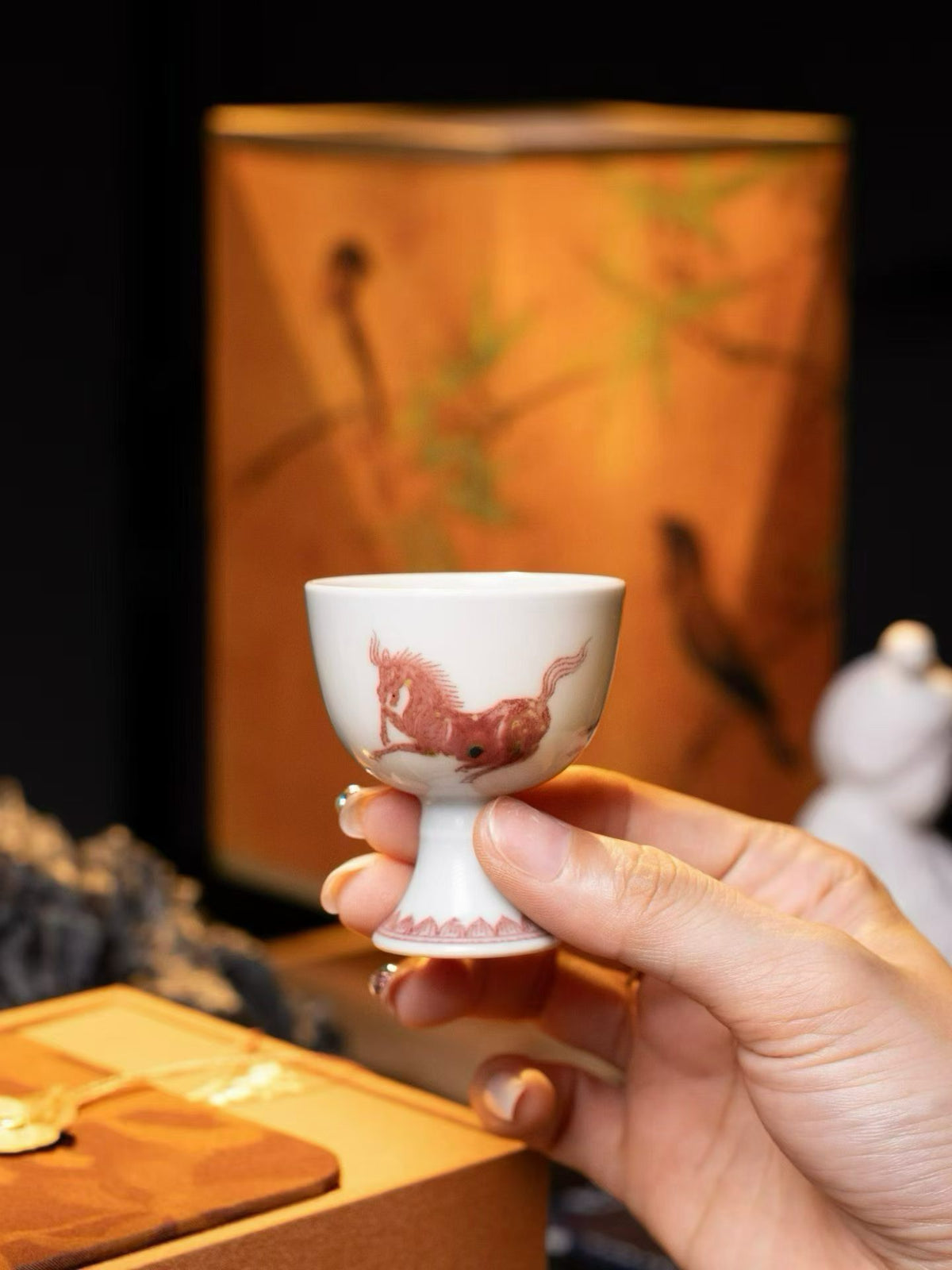 Hand holding a porcelain cup with floral decoration