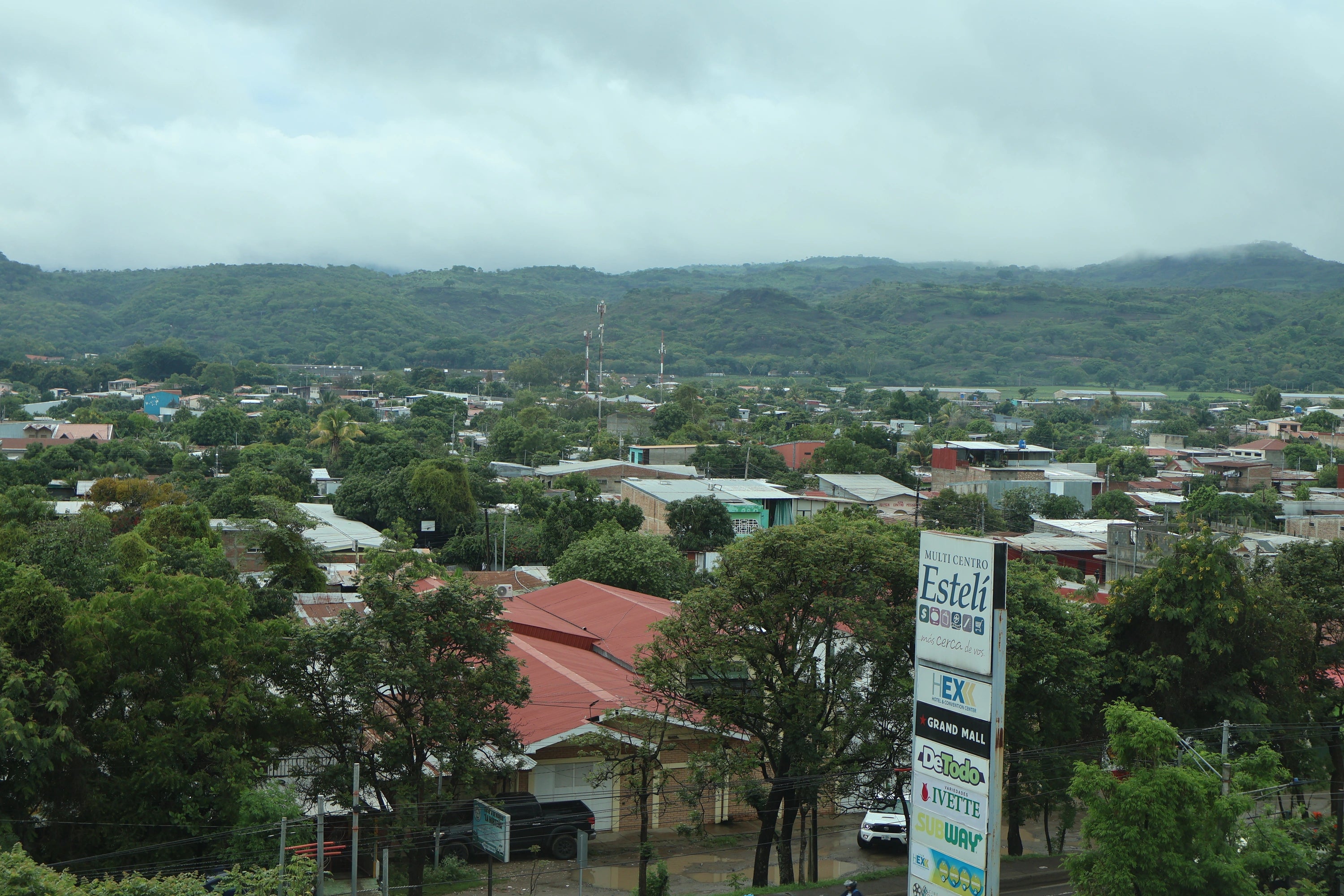 Buildings, trees and a road below green hills beneath a cloudy sky, photographed during the team’s visit to Nicaragua.